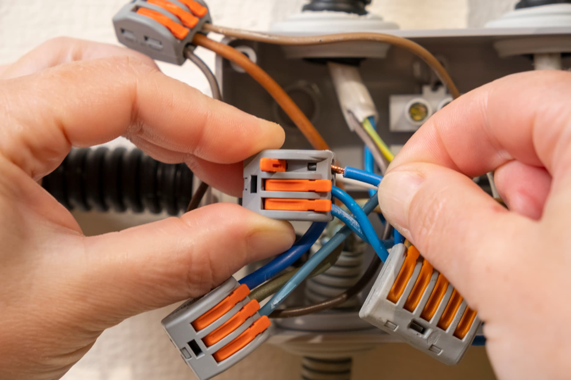 Electrician connecting new circuit cables into lever connectors inside a junction box during a house rewire in Fleet, Hampshire